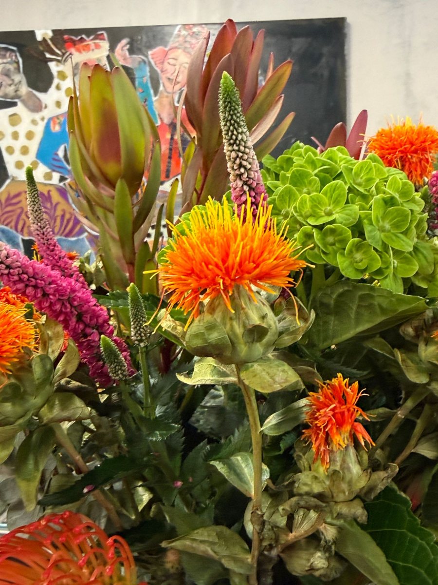 Fresh protea and safflower arrangement in front of a painting, at Pure Space, Gaia